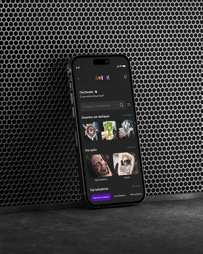 Go Ink app on a phone leaning against a perforated metal wall, home screen with featured designs